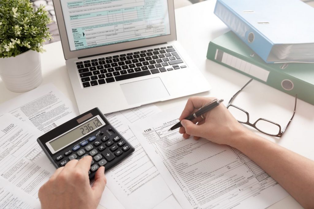 A person using a calculator on a desk with paperwork.