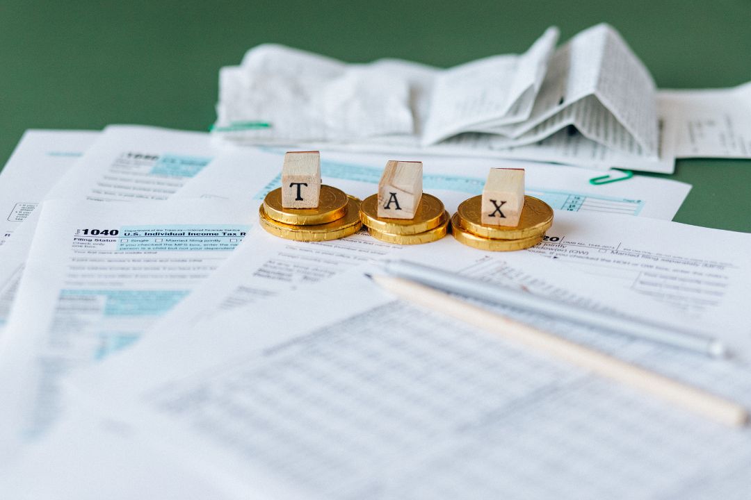 A professional tax advisor's workspace with a stack of tax forms and a pen on a table.