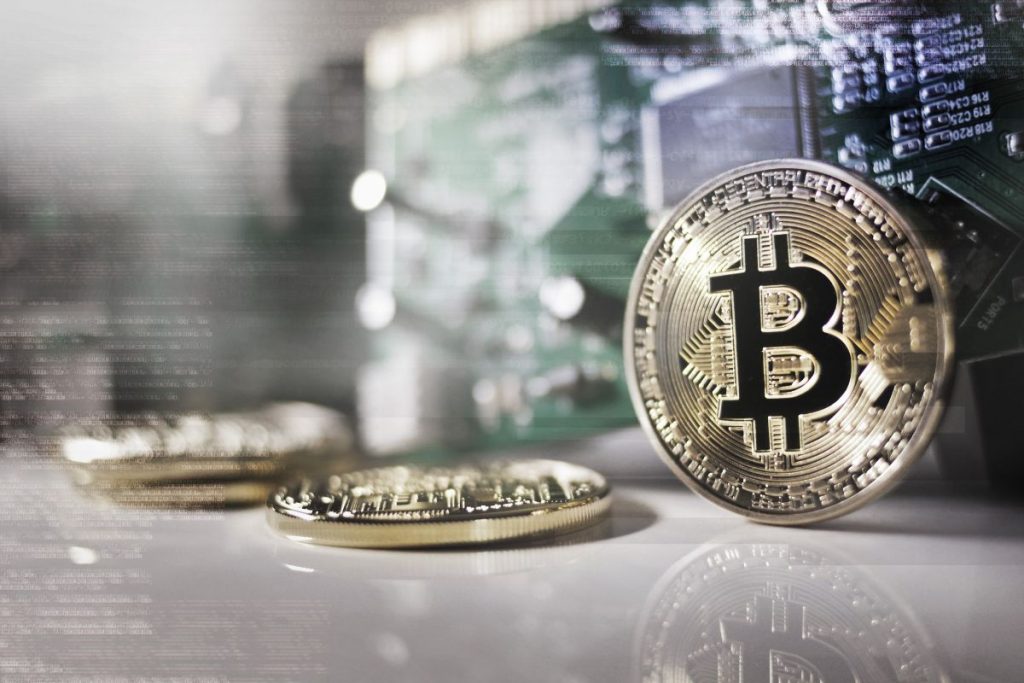 A bitcoin sits on top of a circuit board.