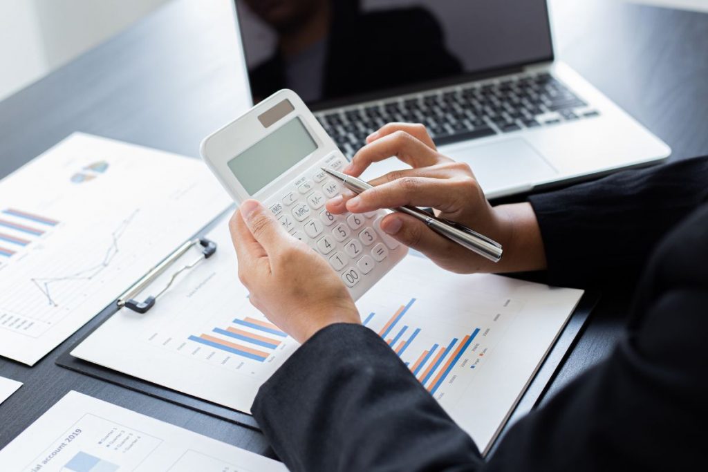 A businessman using a calculator on a desk.