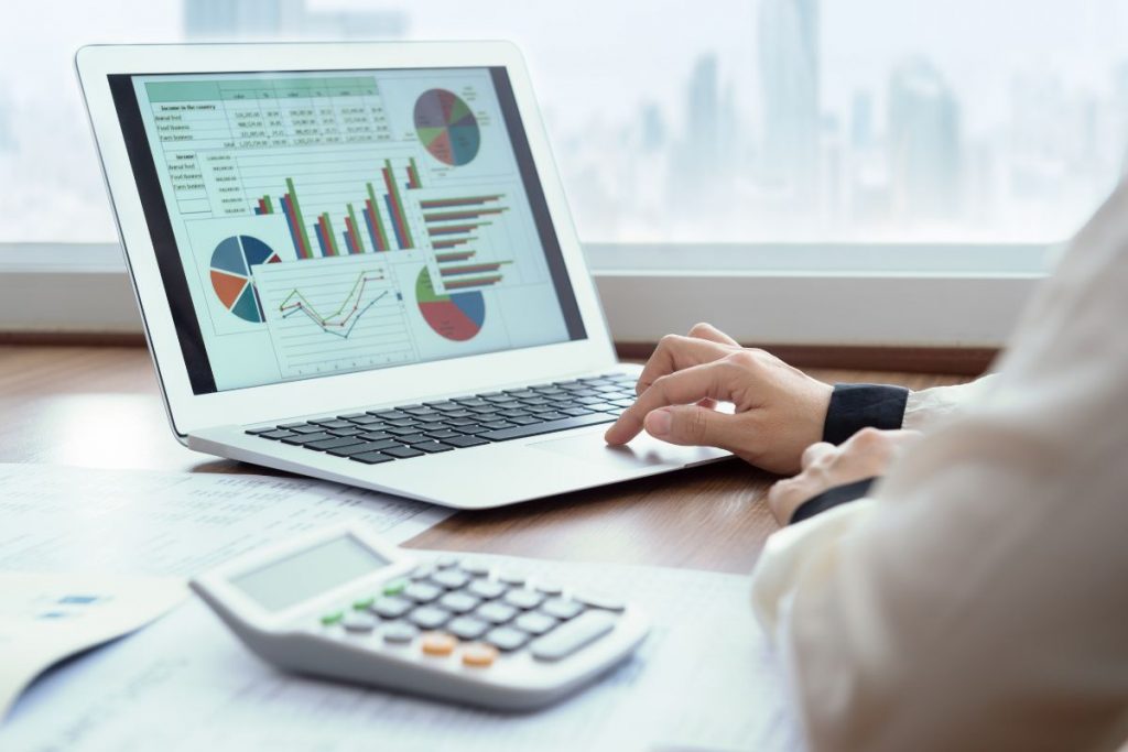 A woman is using a laptop with graphs on it.