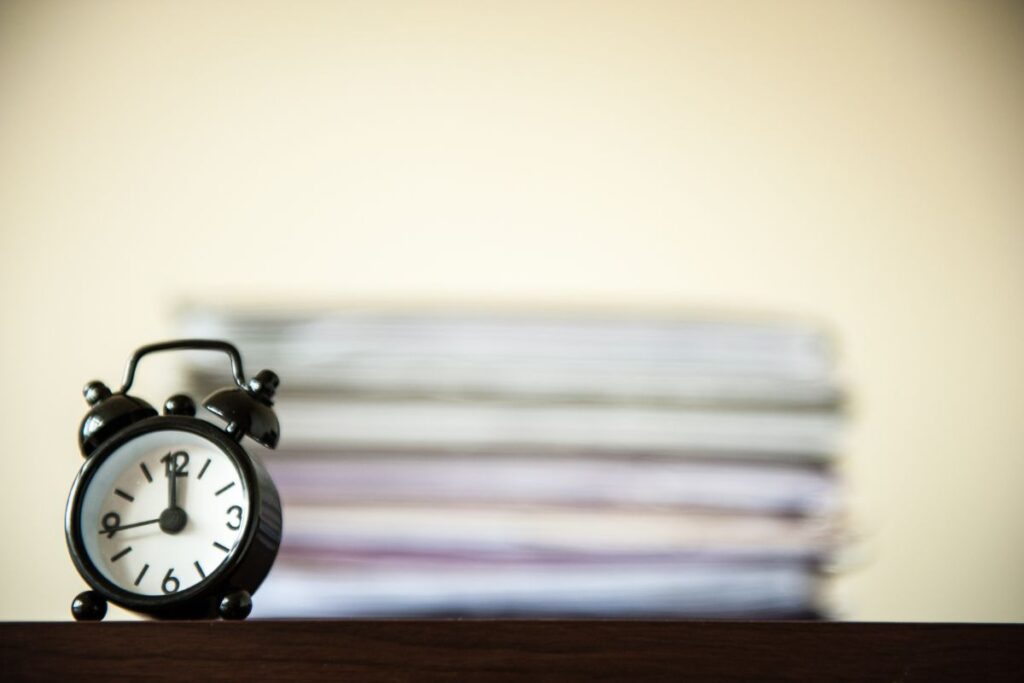 An alarm clock sits on top of a stack of papers.