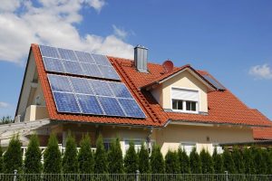 A house with a red-tiled roof has several solar panels installed on one side, taking advantage of the credits before the 2026 Home Energy Credit Sunset, all under a clear blue sky.